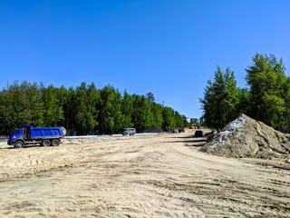 Noyabrsk, Russia - June 8, 2022: Road equipment mounds and levels the sand for a new road on Lenin...