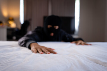 Blurred burglar on bed in sleeping room.