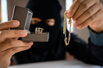 Thief holding jewelry indoor. Robbery concept.