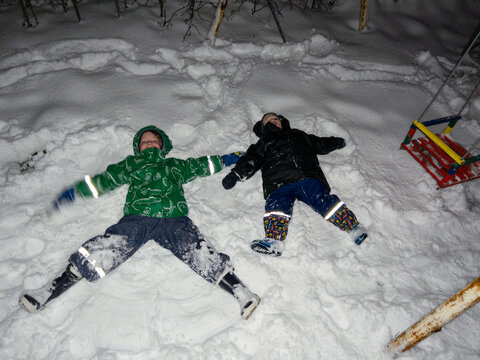 Smiling children lay on the snow during the night