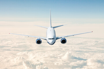 A passenger airplane flies above the clouds