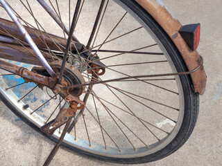 Rusty old bicycle wheel parked on the side of the road. - 522179234