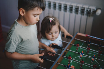 Big brother spending playtime with his younger sister playing foosball together. Sports football...