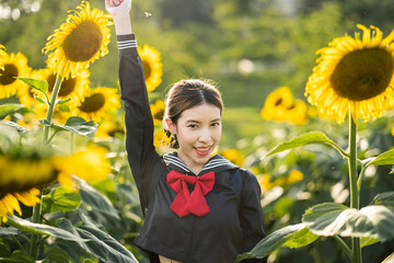 Woman wearing cosplay Japanese school uniform at sunflower garden outdoor.