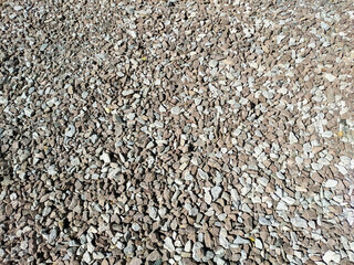 Gravel road. Gravel texture. Stone background. The stones are gray and brown. Top view