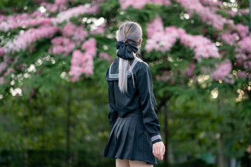 Woman wearing cosplay Japanese school uniform at park outdoor.