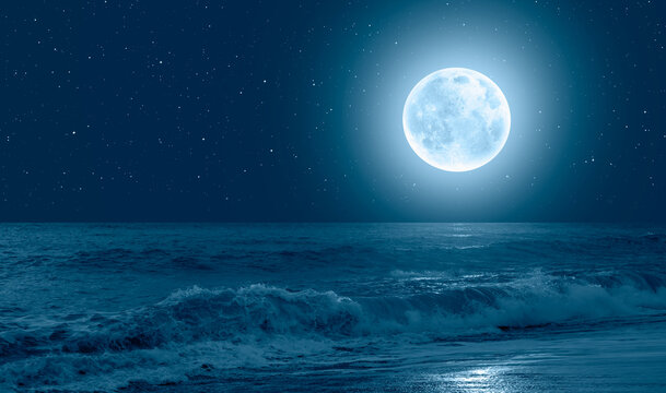 Night sky with blue moon in the clouds sea wave in the foreground 
