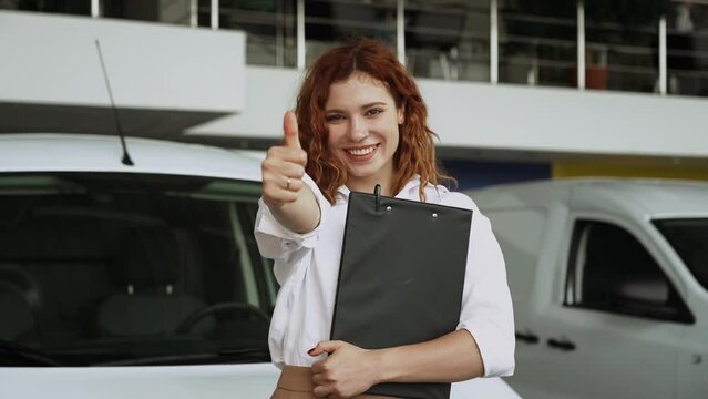 Attractive woman consultant of car center standing near car.Auto rental or sales concept