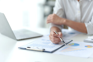 Close-up of business woman hands to check company finances and earnings and budget. Business people calculating monthly expenses, managing budget,  papers, loan documents, invoices.