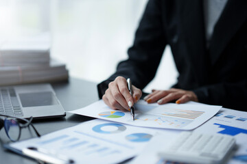 Close-up of business woman hands to check company finances and earnings and budget. Business people calculating monthly expenses, managing budget,  papers, loan documents, invoices.