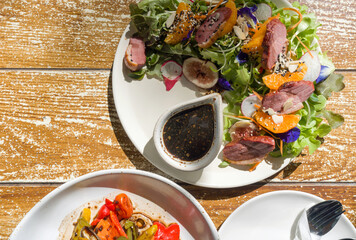 Smoked duck breast salad with balsamic sauce and Grilled organic salad served on wooden table. Top View