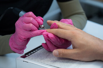 The master makes a hardware manicure to a male client. 