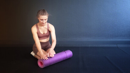 Fitness woman. Fit girl looking away sitting on a pink yoga mat is exercising pilates in the gym. Class Stretching in the gym on a black rubber covering. Stretching and lose weight. Top view overhead.