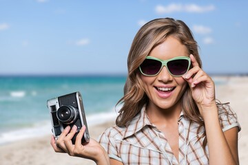 Portrait of smiling woman wearing fashion sunglasses at the beach. Beautiful young woman at sea