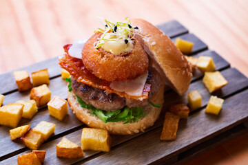 Mini gourmet hamburger with fried onion, lettuce and bacon.