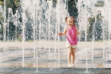 Happy kid playing in a fountain with water