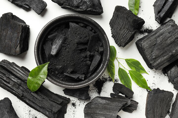 Charcoal, powdered charcoal and leaves on white background