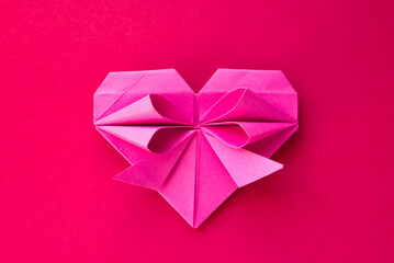 Pink paper heart origami isolated on a red background