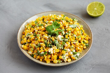 Homemade Mexican Street Corn Esquites on a Plate on a gray background, side view.