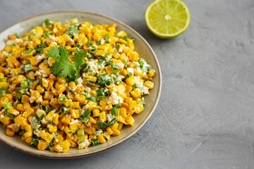 Homemade Mexican Street Corn Esquites on a Plate on a gray surface, side view. Copy space.