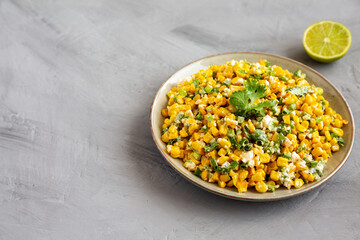 Homemade Mexican Street Corn Esquites on a Plate on a gray background, side view. Space for text.