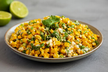 Homemade Mexican Street Corn Esquites on a Plate on a gray background, side view.
