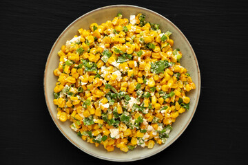 Homemade Mexican Street Corn Esquites on a Plate on a black background, top view. Flat lay, overhead, from above.