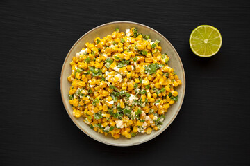 Homemade Mexican Street Corn Esquites on a Plate on a black background, top view. Flat lay, overhead, from above.