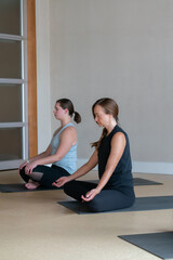 Fototapeta na wymiar two women doing yoga in modern studio