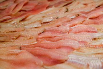 Lot of fish fillets lying on the counter in the shop window. Close-up, selective focus