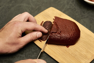 a man cuts a basturma on a wooden chopping board next to a plate of spices