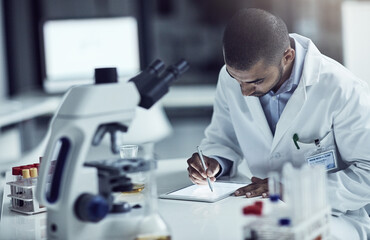 Scientist, researcher and medical technician writing on a tablet, recording information and results in a lab. Focused and serious worker using technology for innovation and research in a laboratory