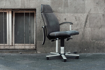 an old office chair in front of a house wall