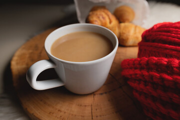 cozy autumn evening: coffee, knitting and croissants, close-up lie on a table and a wooden tray