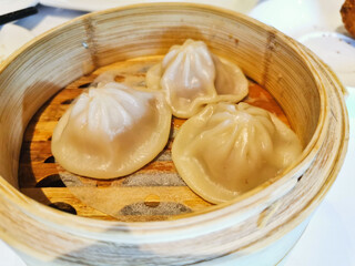 Xiao Long Bao soup dumpling with pork inside in bamboo basket in Yum Cha Chinese restaurant