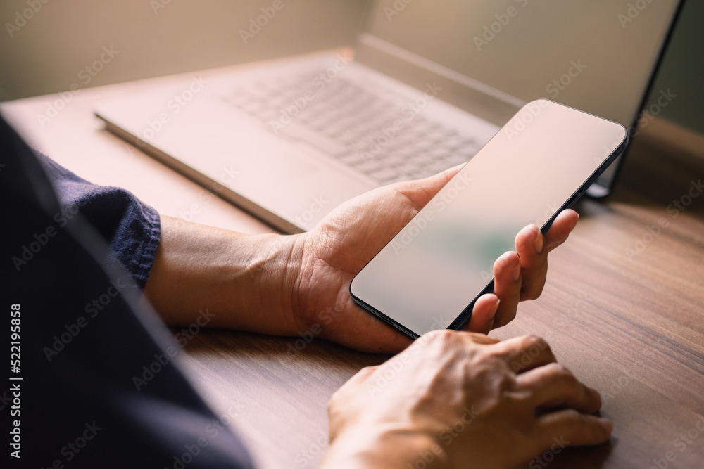 Poster Mockup image of a man holding and using smartphone with blank desktop screen while working and drinking coffee in cafe.