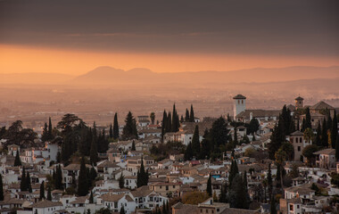 Evening cityscape view of the historic Moorish or Arab Quarter (Albaicín) in Granada with mountains in background, Andalusia, Spain.
