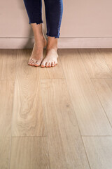 Woman sitting and barefoot relaxing on wooden floor in home environment. Copy space.