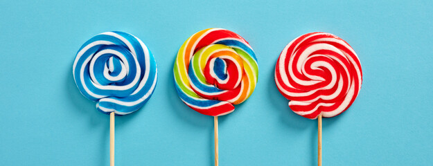 Colorful swirl round candy lollipops on blue background.
