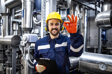 Successful power production and refinery worker holding okay sign.