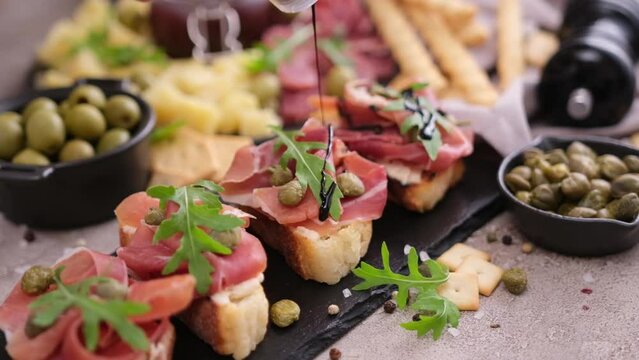 Making bruschetta with prosciutto or jamon ham at domestic kitchen