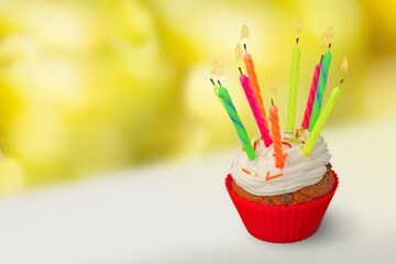Tasty sweet buttercream birthday cupcake with colorful birthday candles and sprinkles