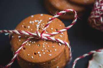 a stack of round-shaped gingerbread cookies tied with a thread of red woolen yarn on a dark background
