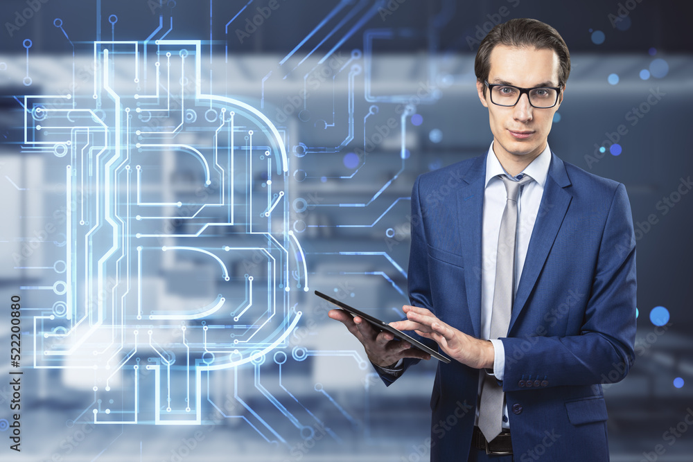 Poster businessman with glasses using tablet with creative glowing bitcoin circuit hologram on blurry offic