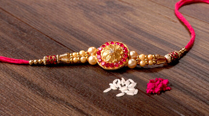Indian Festival: Rakhi with rice grains, kumkum, sweets and haldi on plate with an elegant Rakhi. A traditional Indian wrist band which is a symbol of love between Brothers and Sisters.