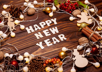 Glowing garland and bokeh effect. Christmas decorations on dark, top view. The postcard for Merry Christmas or Happy New Year on old wooden background.Xmas composition with gifts, toys, inscription