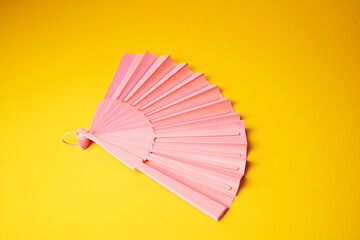 Pink fan on a yellow background. - Summer concept.