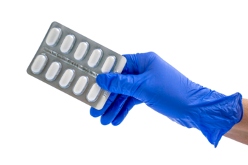 Doctor or scientist hand in blue nitrile glove holds a blister with pills