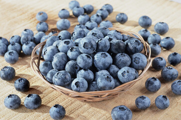 Fresh ripe blueberries - vaccinium myrtillus, in a bowl on a wooden background - obrazy, fototapety, plakaty