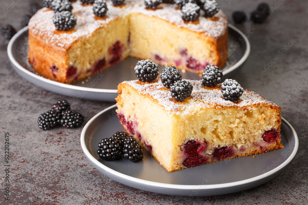 Wall mural piece of cake with fresh blackberries and powdered sugar close-up in a plate on the table. horizonta